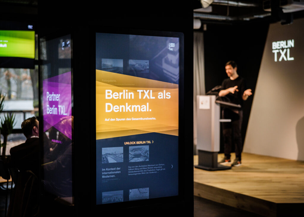 Blick auf eine digitale Informationssäule mit Infotext zu Berlin TXL