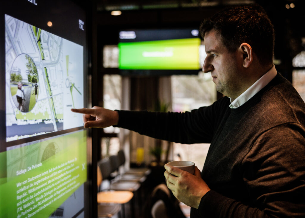 Interessierter Mann informiert sich auf einem Smartboards über Berlin TXL