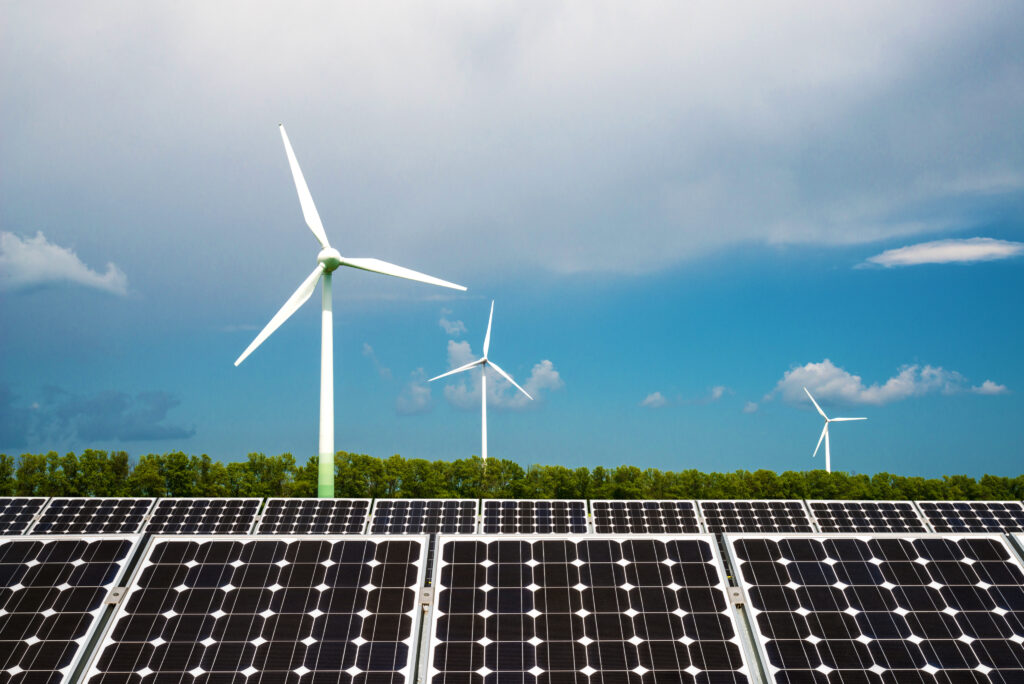 Windräder und Solaranlage in bewaldeter Umgebung