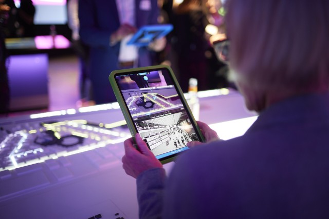 Besucherin im Infocenter Berlin TXL schaut auf ein Tablet im interaktiven Aiusstellungsraum
