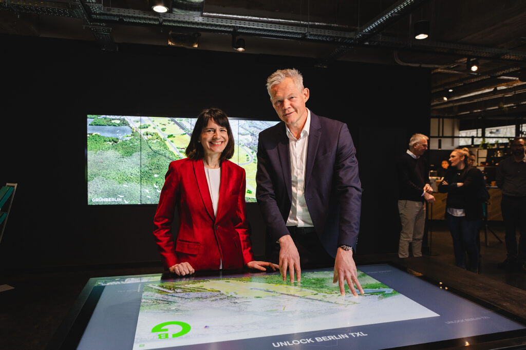 Christoph Schmidt, Geschäftsführer von Grün Berlin, und Britta Behrendt, Staatssekretärin für Klimaschutz und Umwelt, im Infocenter Berlin TXL vor den Plänen zur Tegeler Stadtheide.