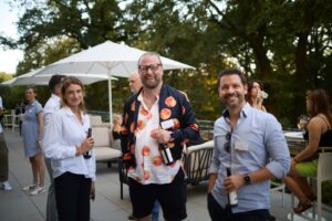 Drei Gäste am Nachmittag der Berlin TXL Summer Lounge auf der Terrasse lächeln in die Kamera.