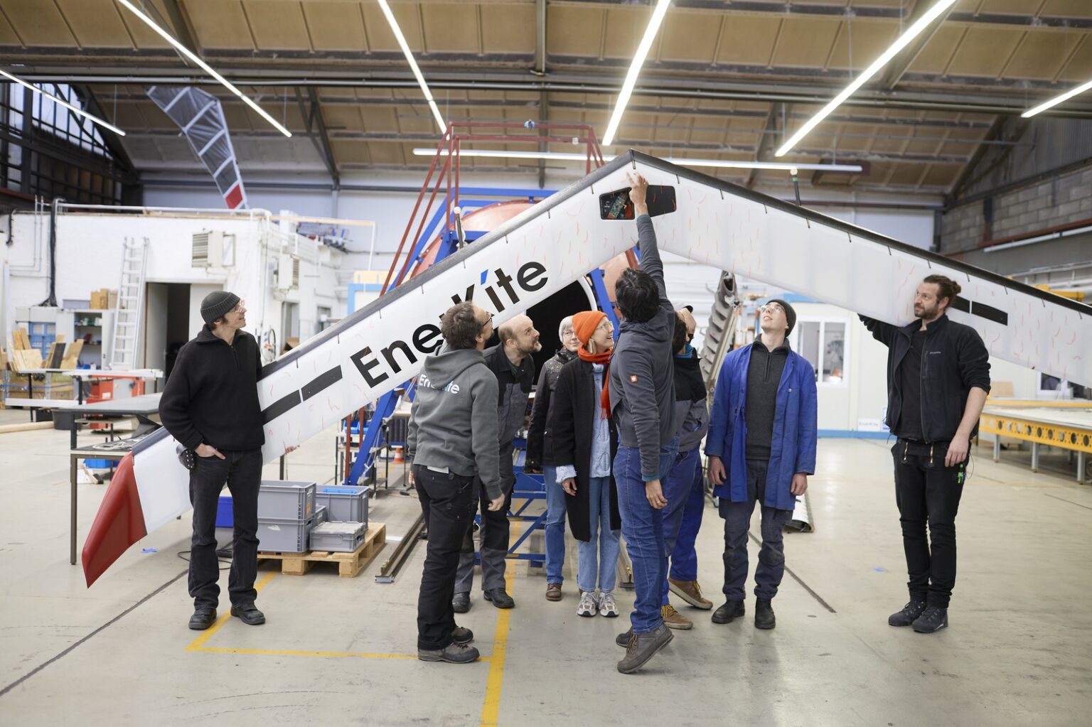 Ein Team von Fachkräften prüft eine große Enerkite-Windkraftanlage in einer Werkstatt.