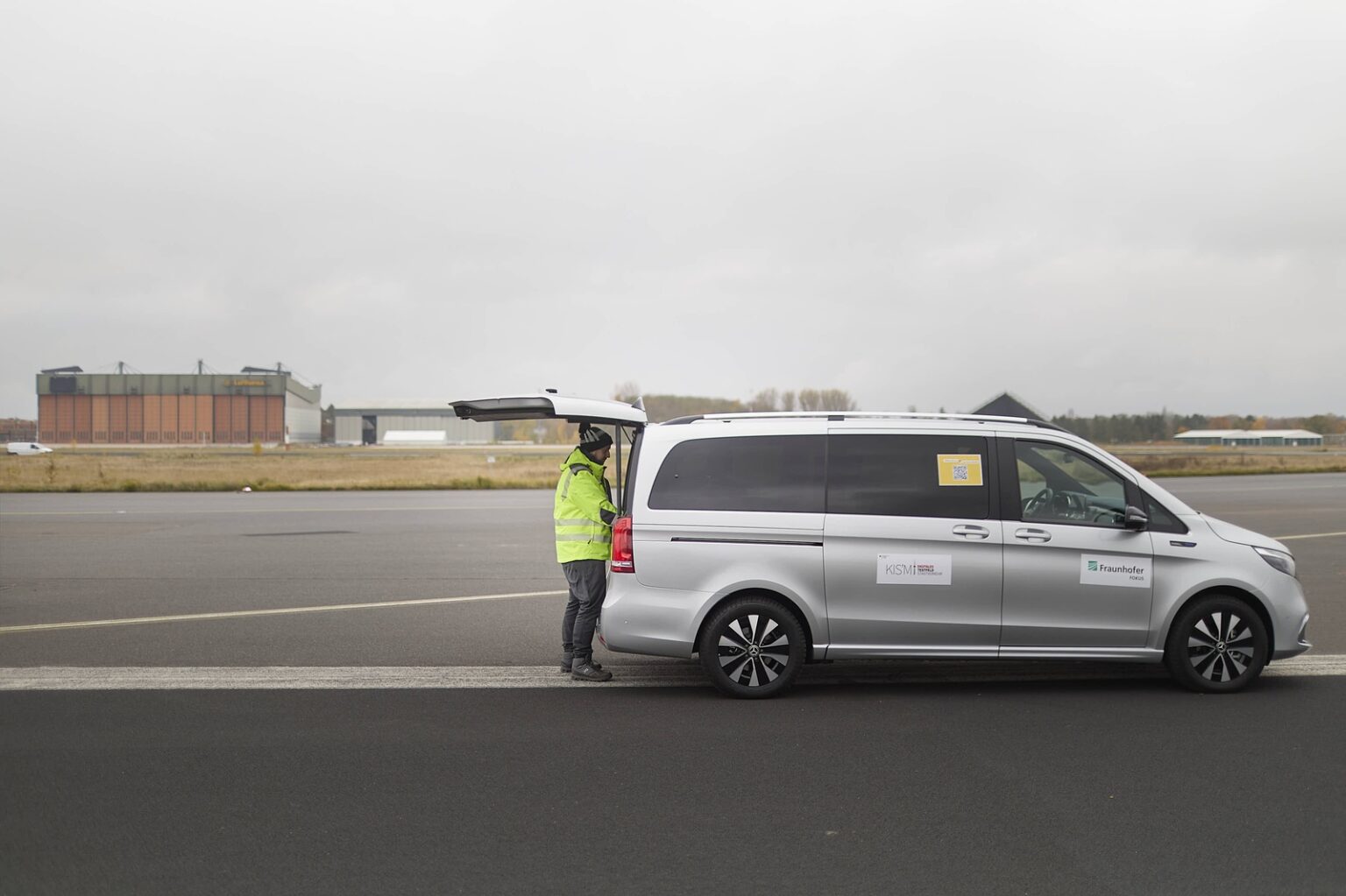 Eine Person in einer Sicherheitsweste arbeitet an einem autonomen Fahrzeug auf einer Start- und Landebahn.